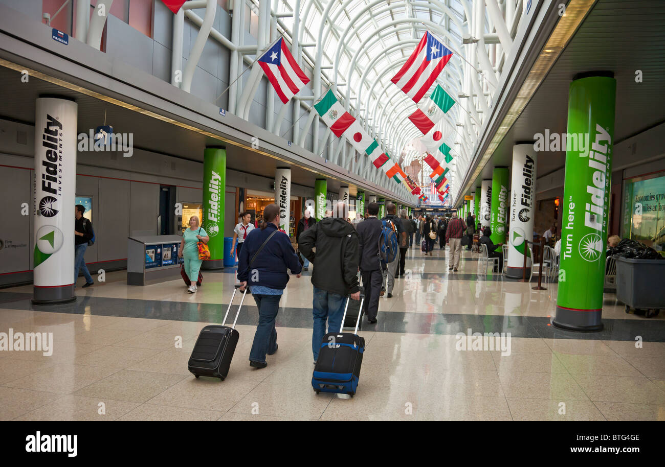 air passengers hauling rolling luggage in Concourse H (American Airlines) of Chicago O'Hare Airport, Illinois, USA Stock Photo