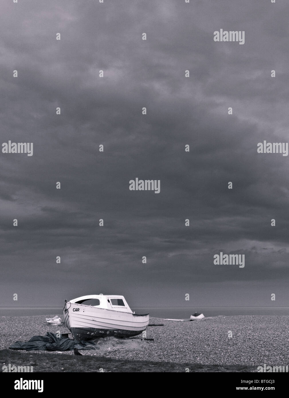 Monochrome image of a small fishing boat on the beach at Aldeburgh with a dramatic sky behind Stock Photo