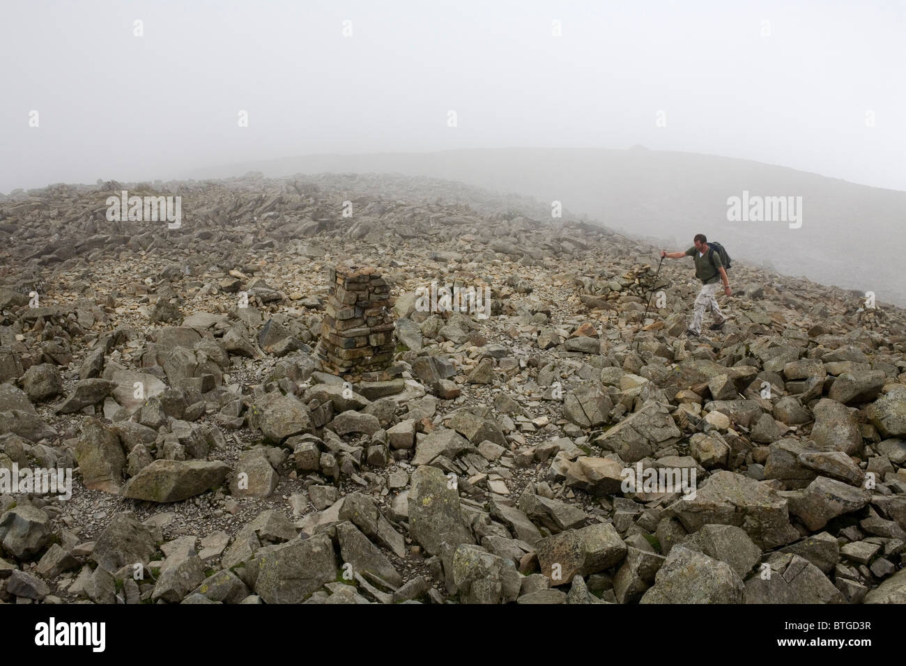 A hiker on the top of Scafell Pike in the Lake District National Park. Stock Photo