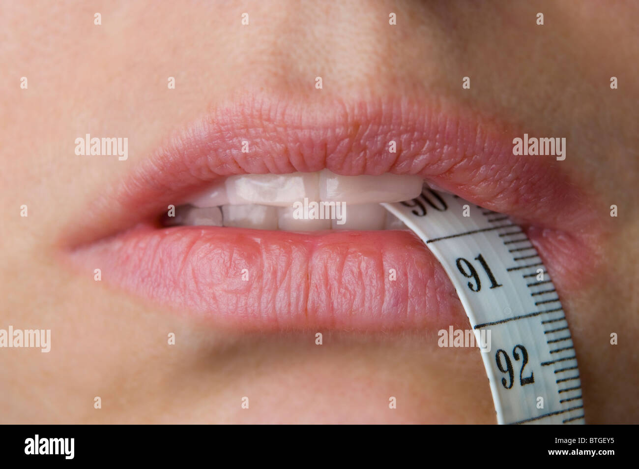womans mouth with tape measure indicating weight loss or gain Stock Photo