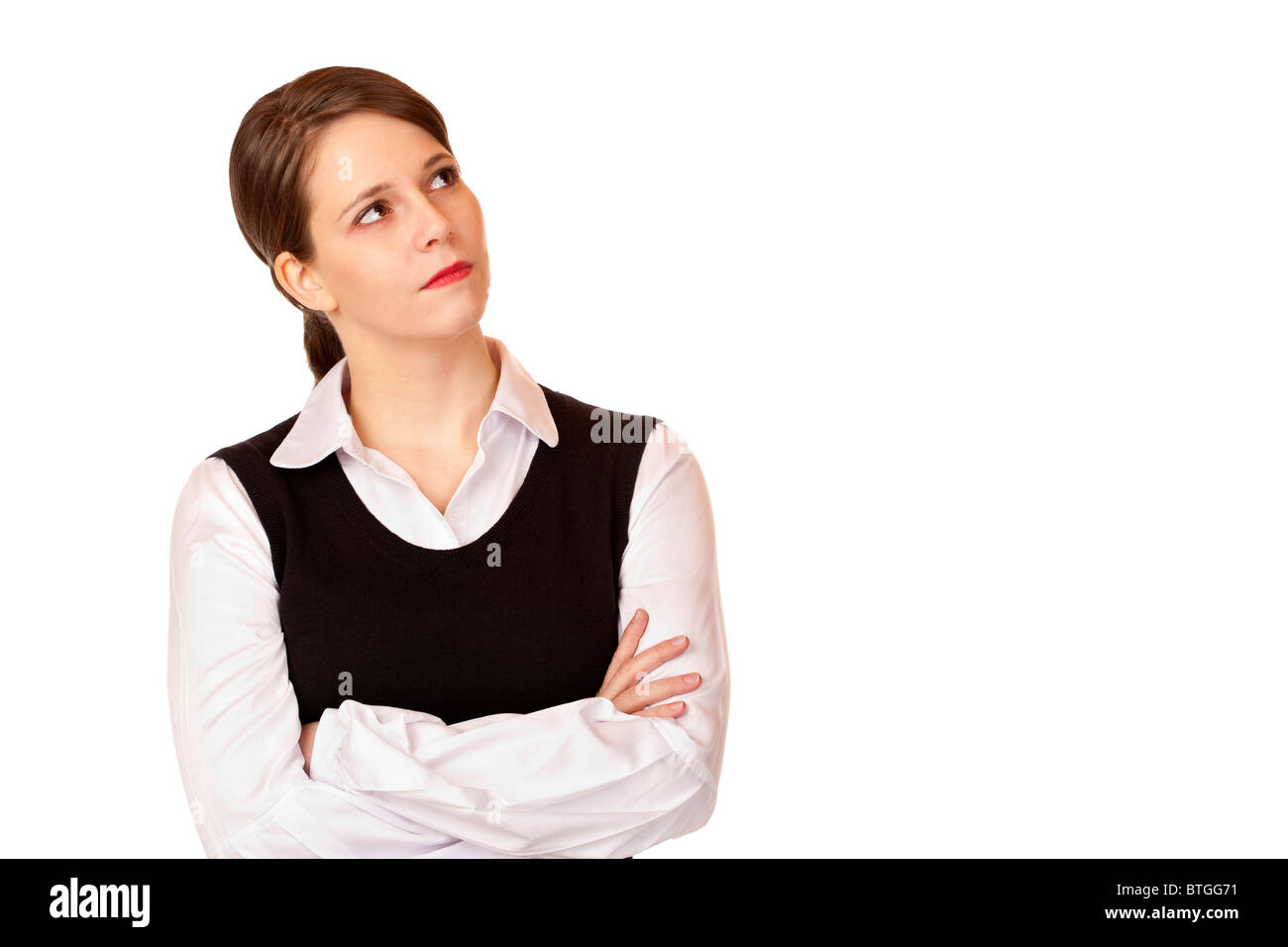 Young businesswoman with crossed arms looks up into the corner. Isolated on white background. Stock Photo