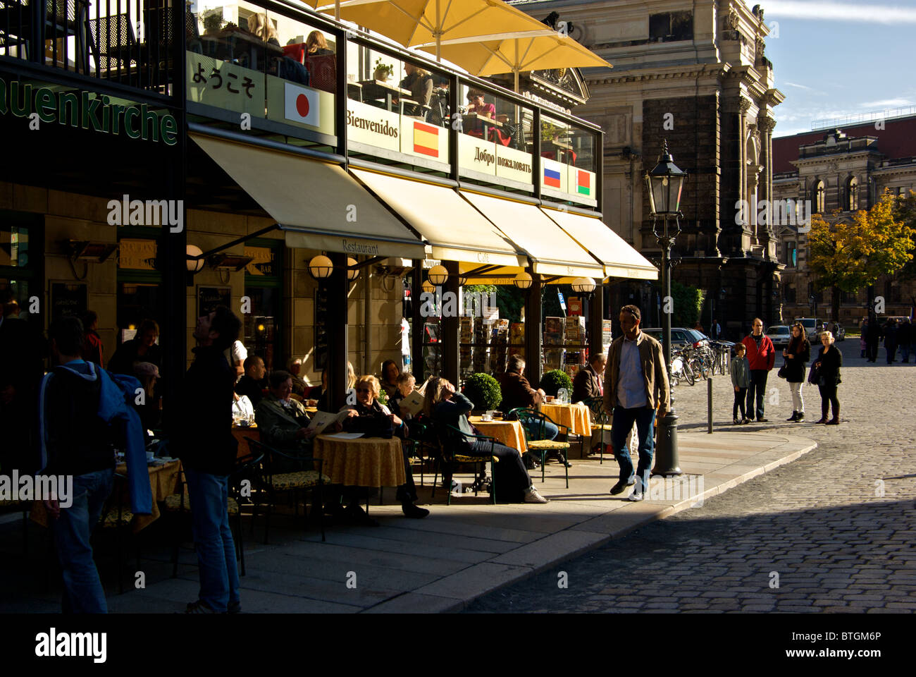 Patrons of corner sidewalk cafe enjoying autumn sunshine in historic old Dresden Altstadt Stock Photo