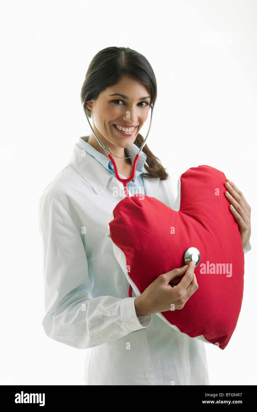 Doctor with stethoscope on heart pillow Stock Photo