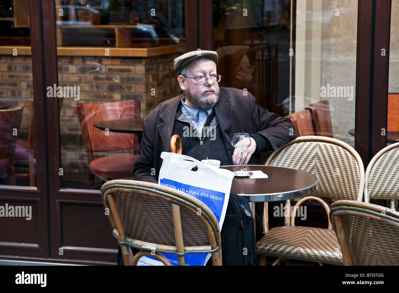 intellectual looking bearded middle aged French man enjoying glass of wine at cafe outdoor seating Boulevard Saint Germain Stock Photo