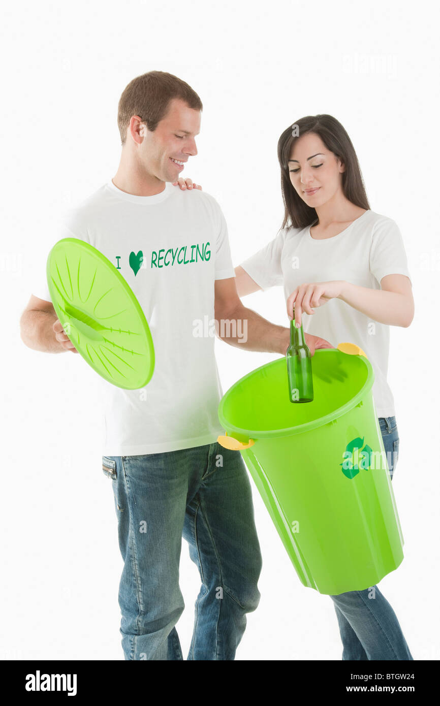 Couple throwing glass bottle in the recycling bin Stock Photo