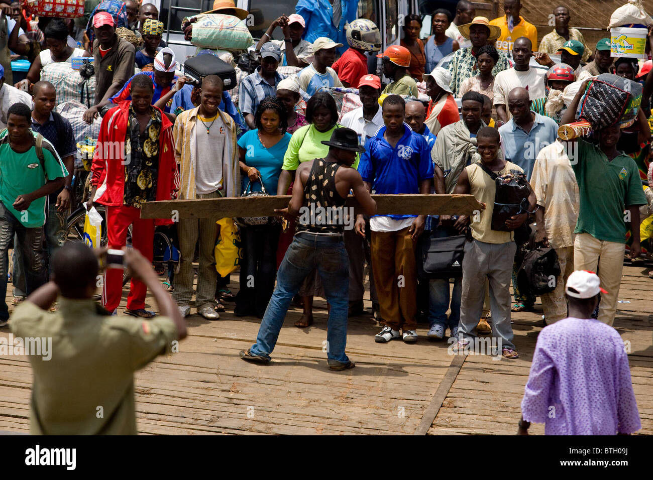 A man tries to control the crowd of passengers on a ferry as it approaches the terminal in Makango, northern Ghana Stock Photo