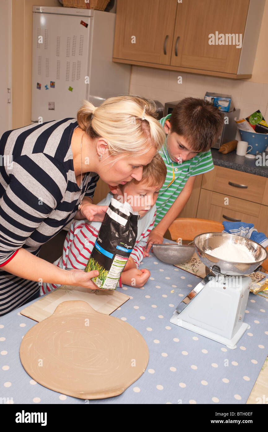 A MODEL RELEASED photo of 2 boys ( 7 & 10 ) and their mum weighing out cooking ingredients in the Uk Stock Photo