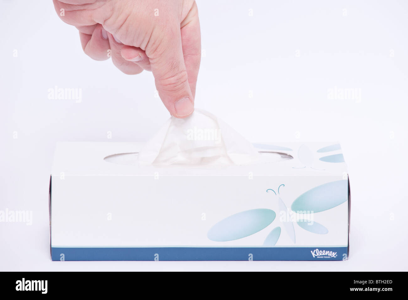 A MODEL RELEASED picture of someone taking a tissue from a box of Kleenex original brand tissues on a white background Stock Photo