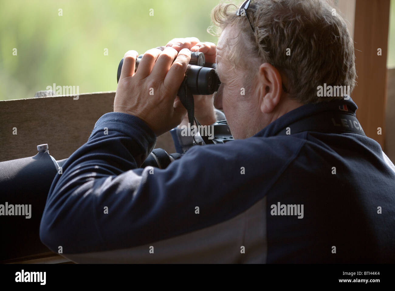 Bird watcher and wildlife Photographer. Using binoculars and the provision of a public hide on a nature reserve. Norfolk. Stock Photo
