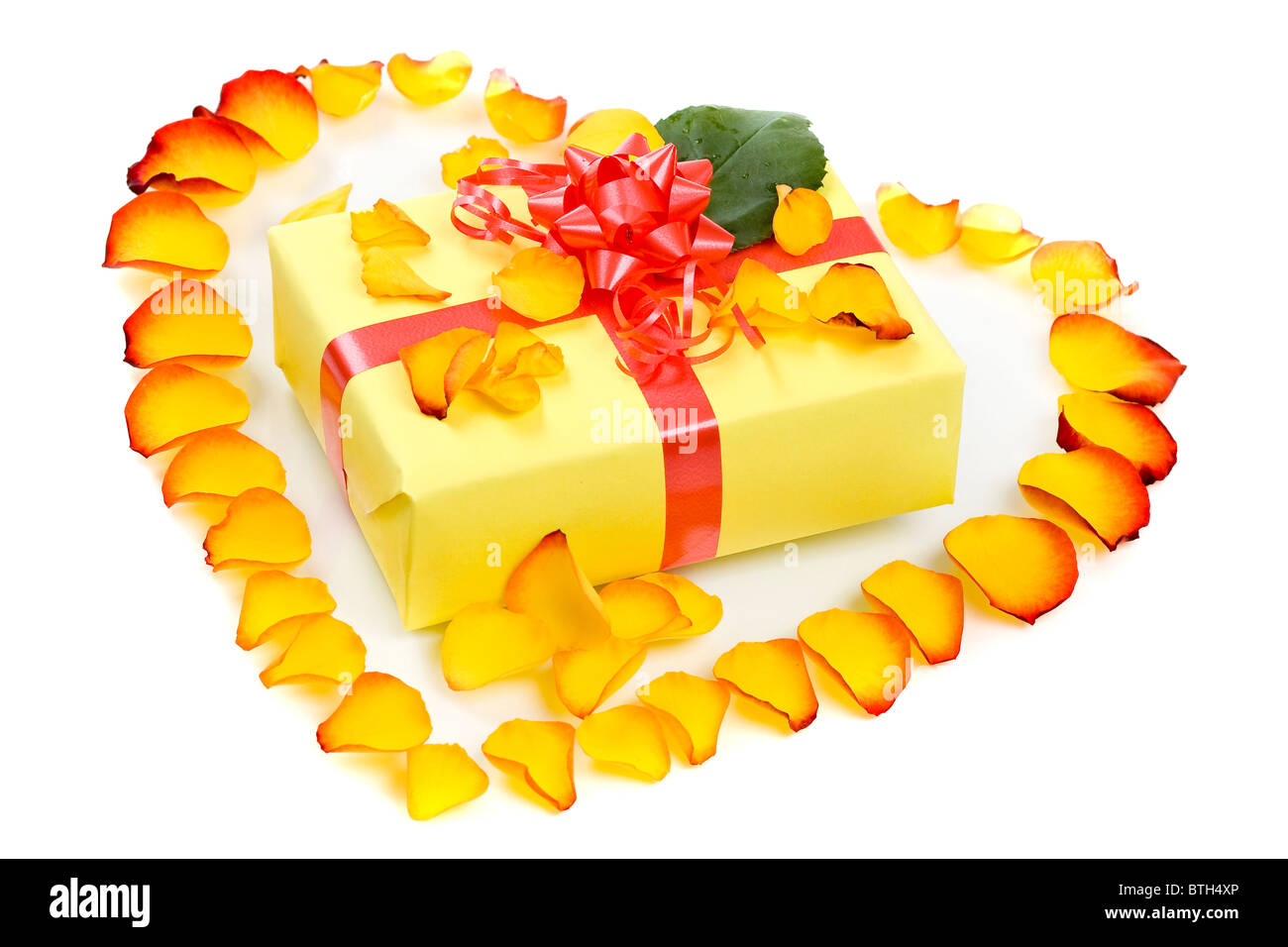 rose petals arranged in a heart shape around the gift Stock Photo