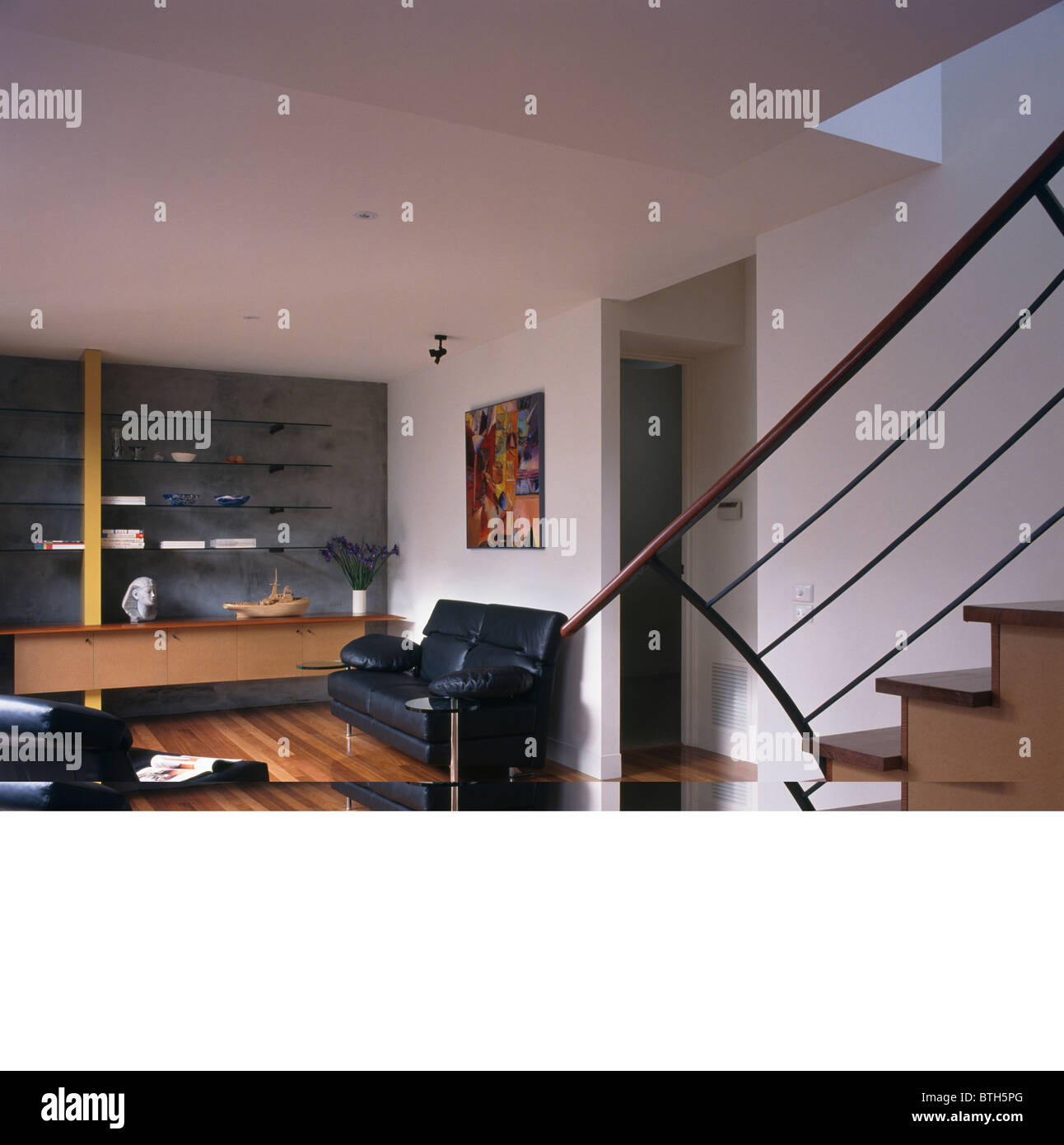 Black leather sofas in modern white openplan living room with wooden