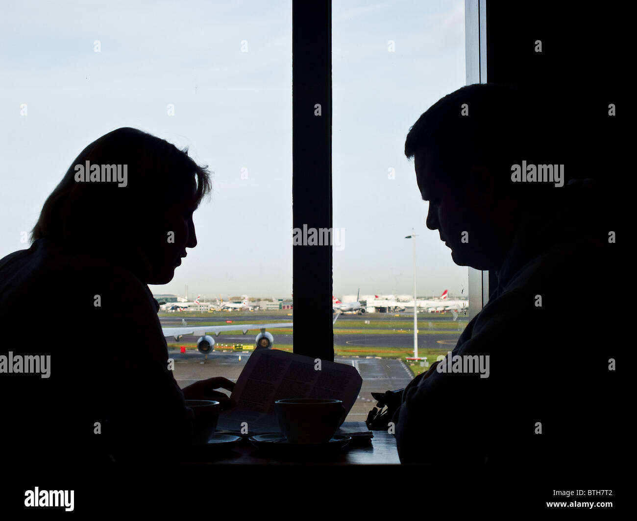 The silhouette of 2 people in an airport lounge. Stock Photo