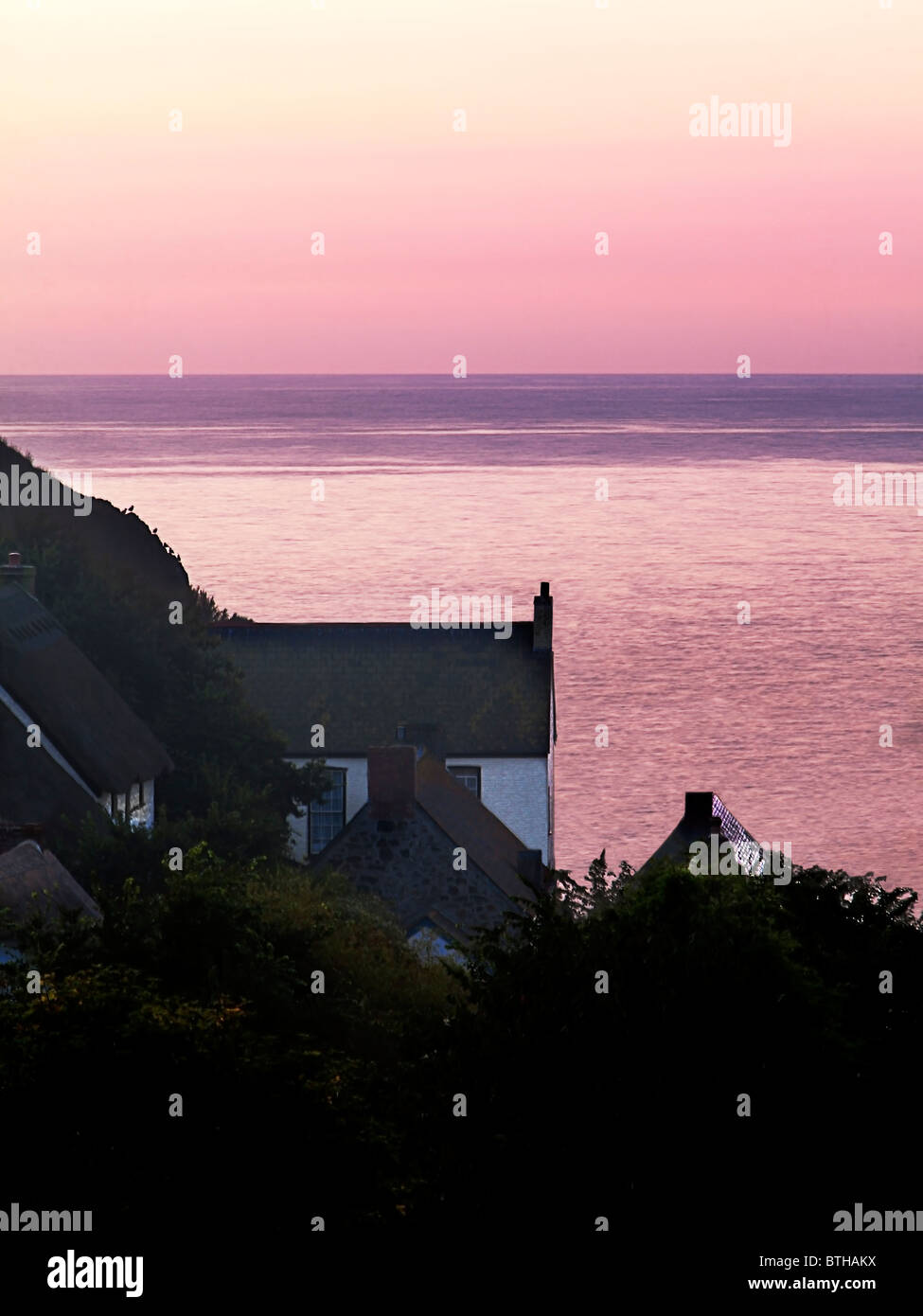 Fisherman's cottages silhouetted against the dawn colours at the fishing village Cadgwith Cove, Cornwall. Stock Photo