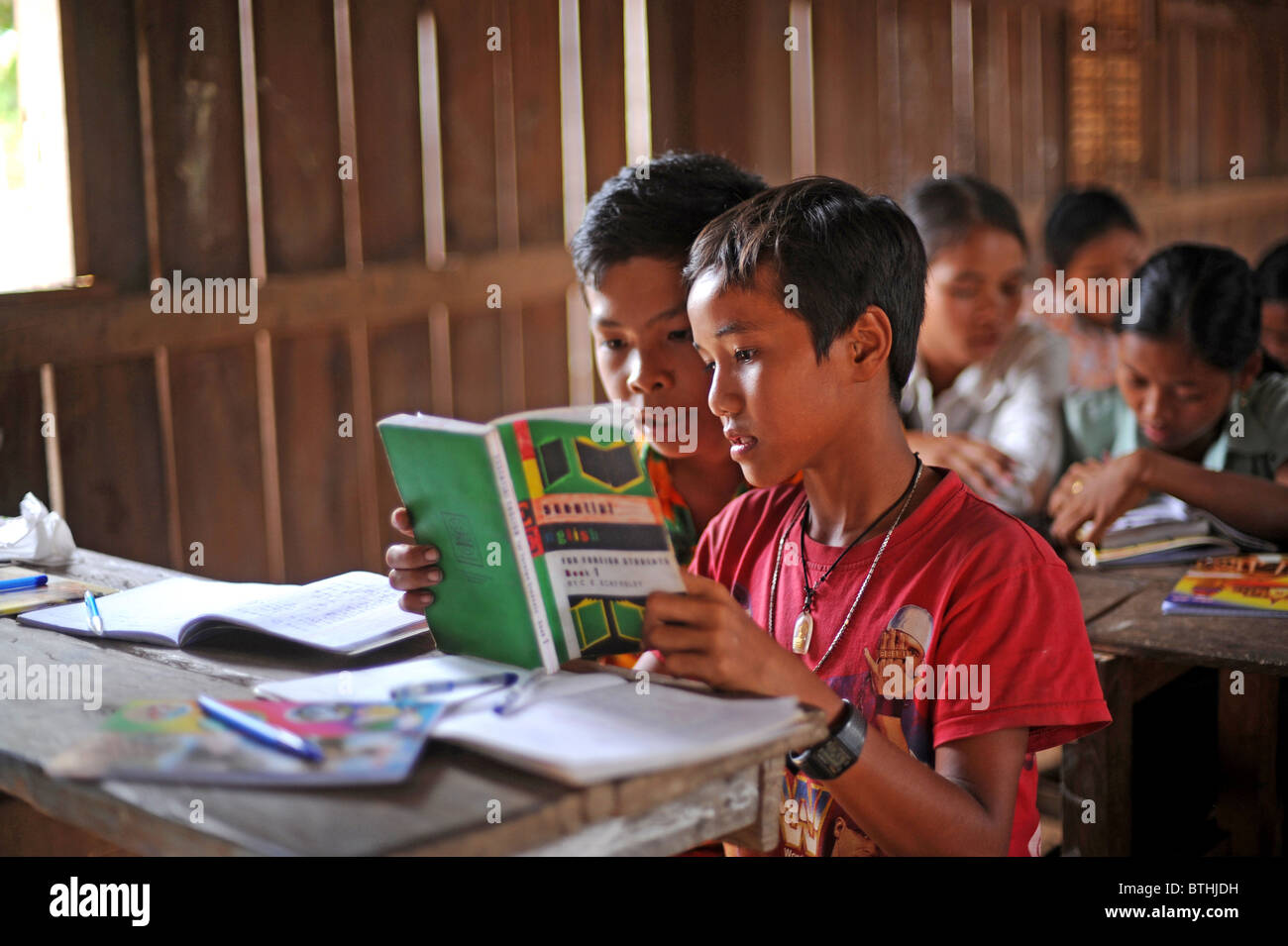 Two students sharing one textbook, Phum Chikha, Cambodia Stock Photo