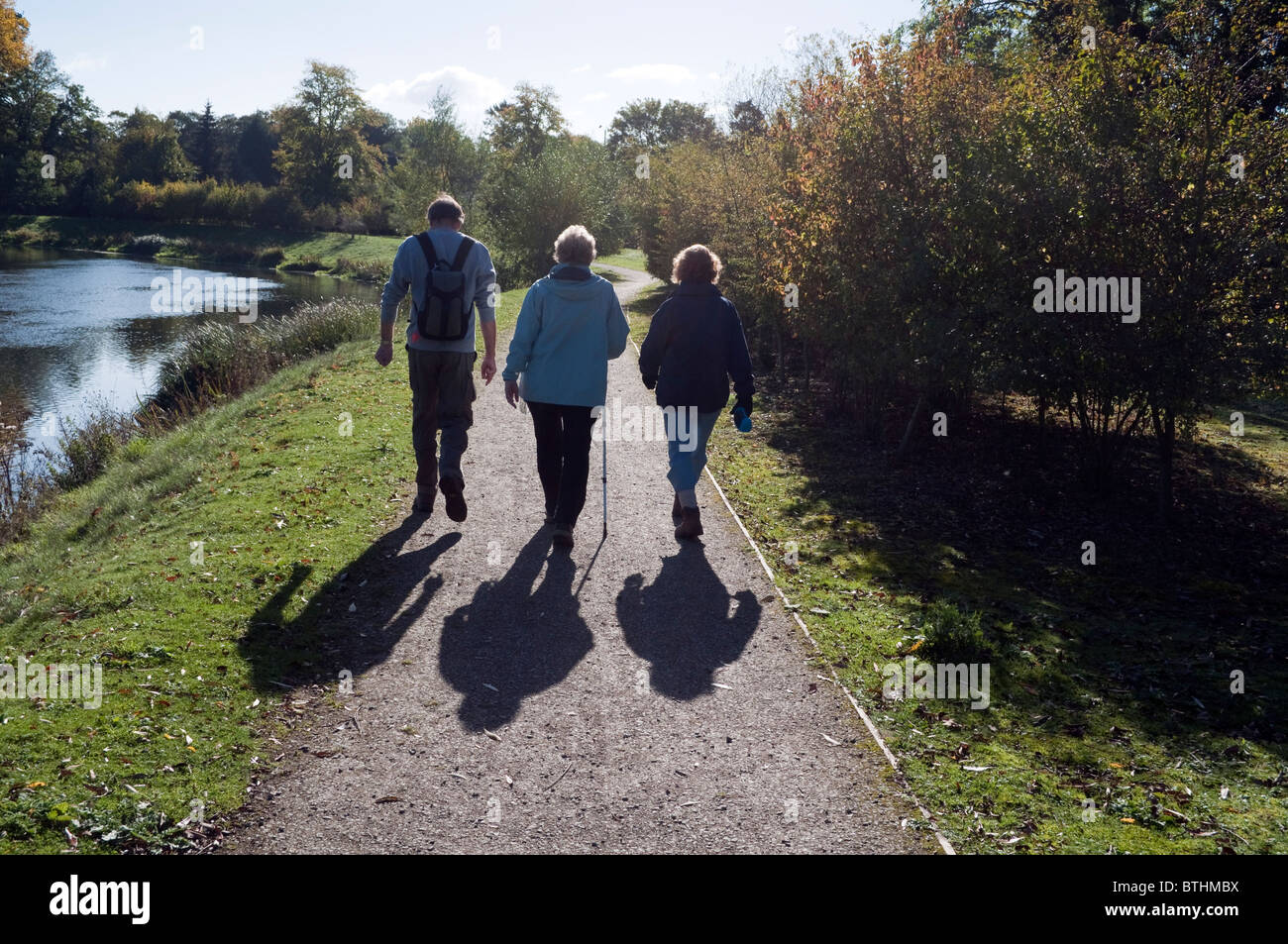 three walkers walking on a footpath on the banks of the Jubilee River at Lake End near Dorney Berkshire UK Stock Photo