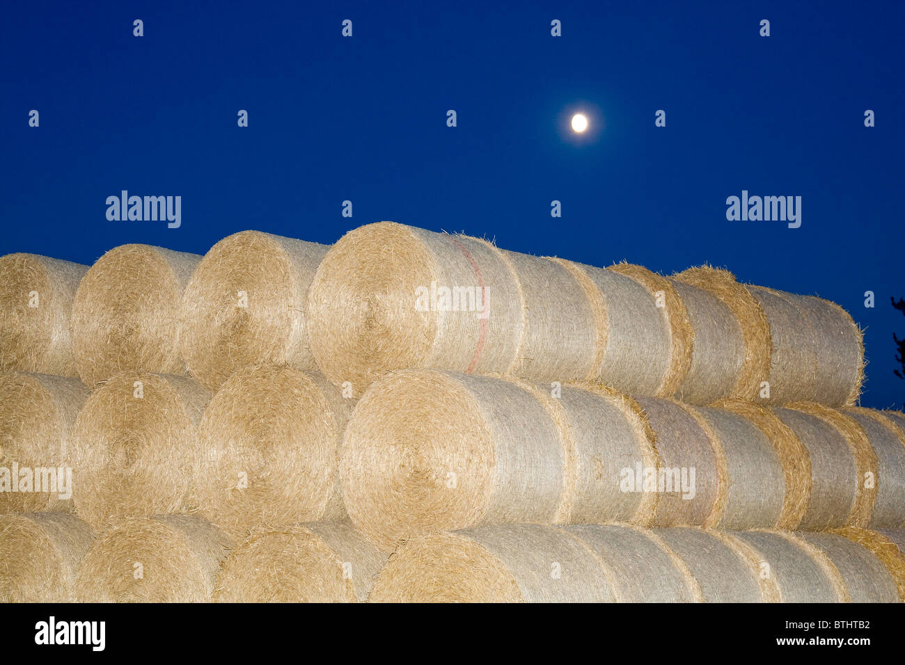 Circular Straw Bales at Night with Moon Stock Photo
