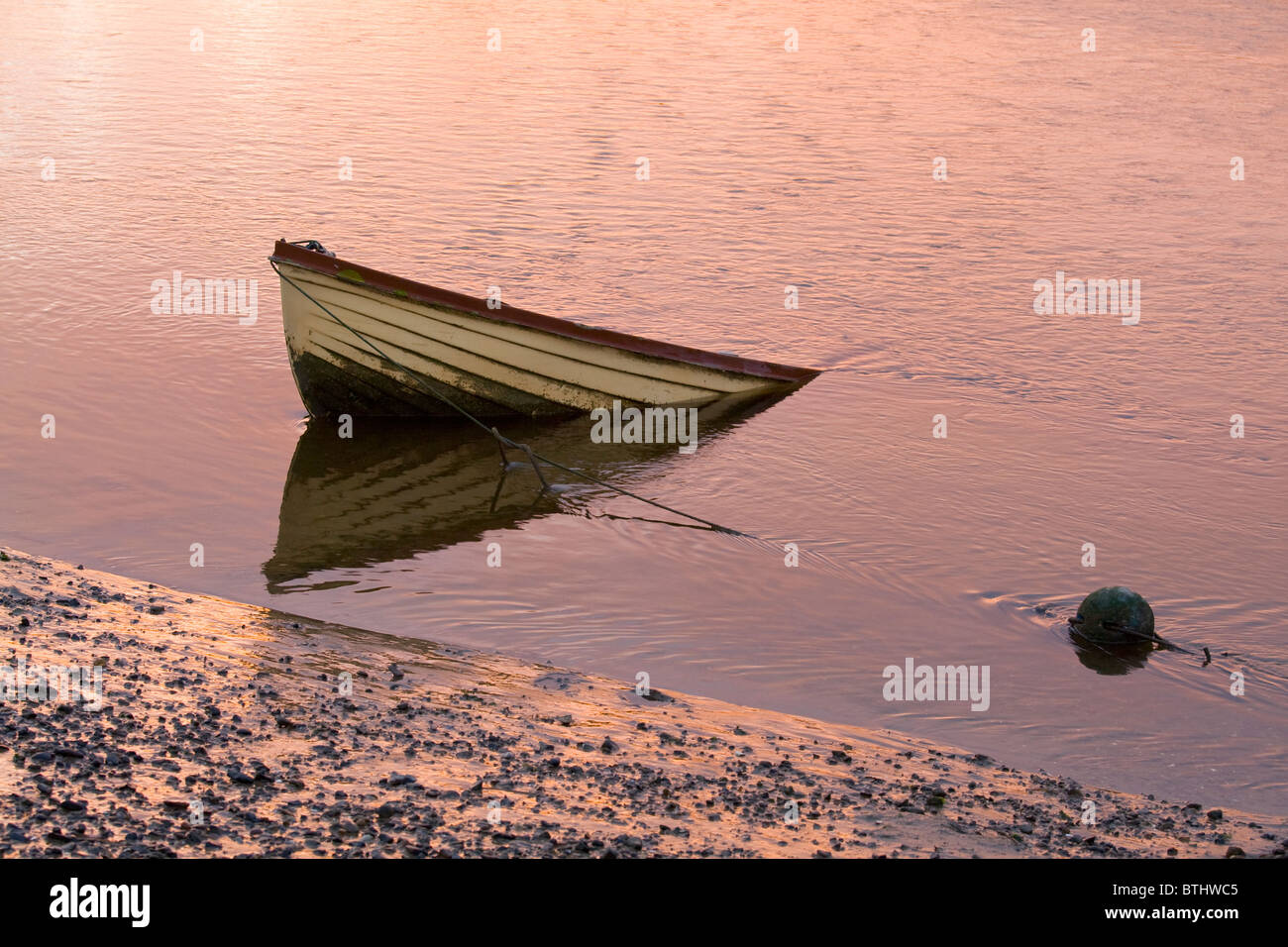 Partly Submerged Rowing Boat at Sunset Stock Photo