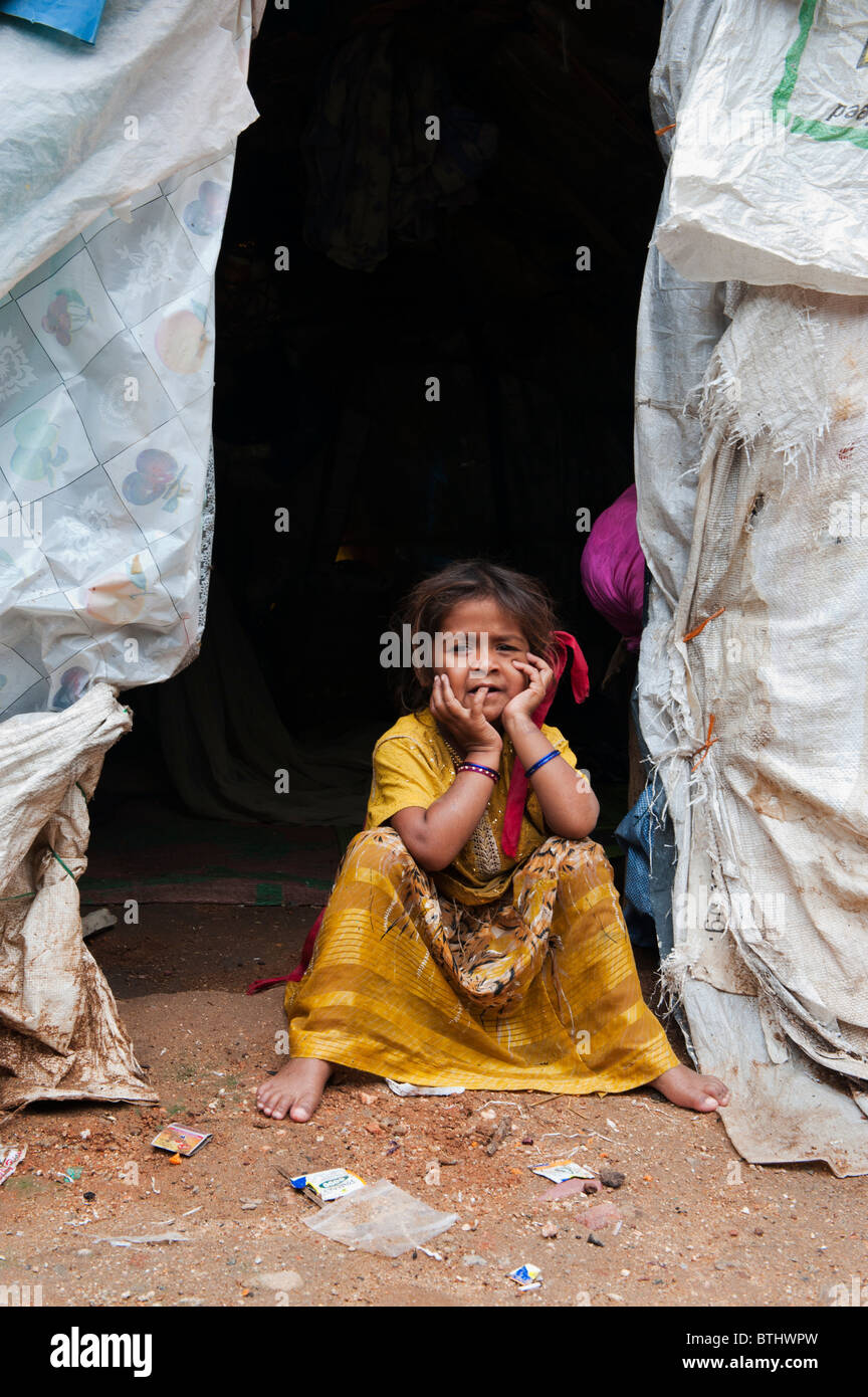 Poor indian girl sitting at the entrance of her tent home. Andhra Pradesh, India Stock Photo