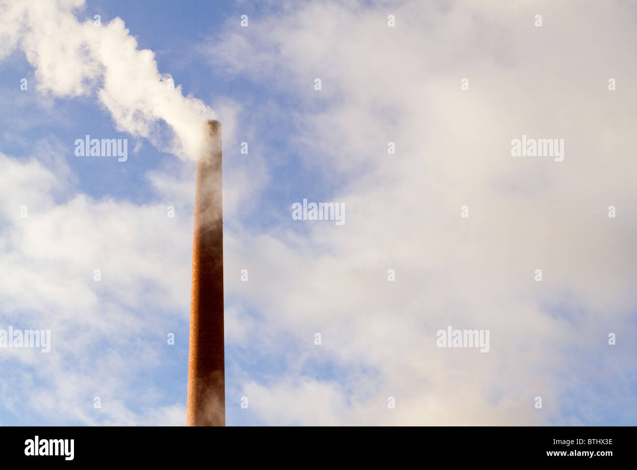 Redbrick chimney with steam and clouds Stock Photo