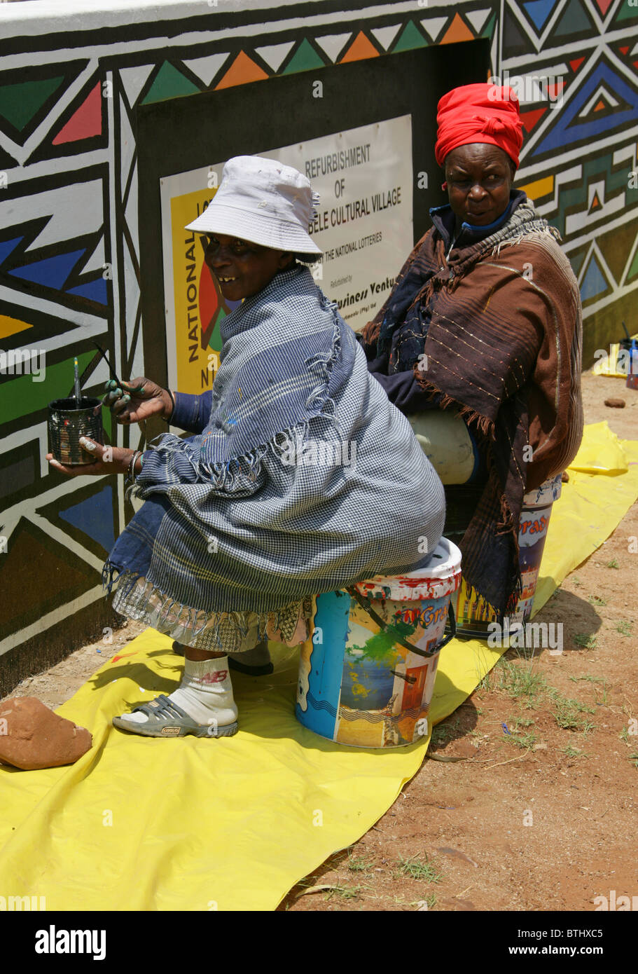 Ndebele Women Painting Traditional Designs on Walls, Ndelebe Cultural Village, Botshabelo, South Africa. Stock Photo