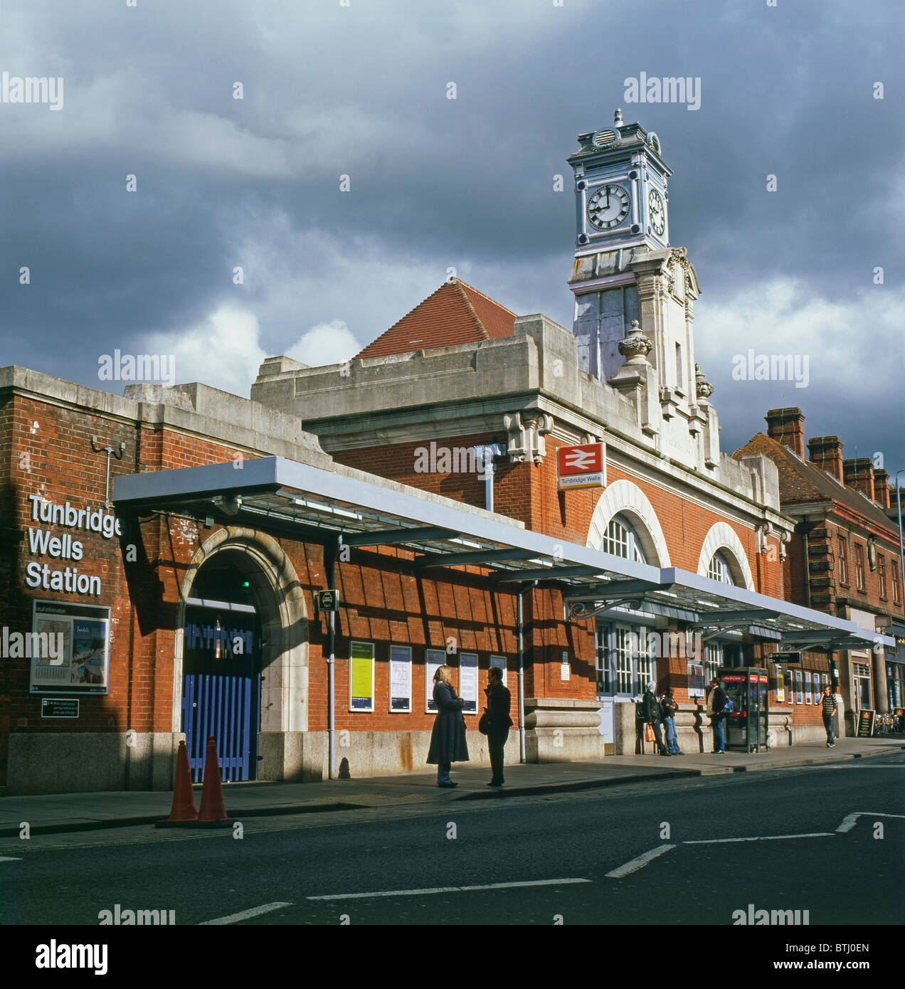 People standing waiting talking outside Tunbridge Wells Railway Station building with clock tower in Kent, England UK Great Britain   KATHY DEWITT Stock Photo