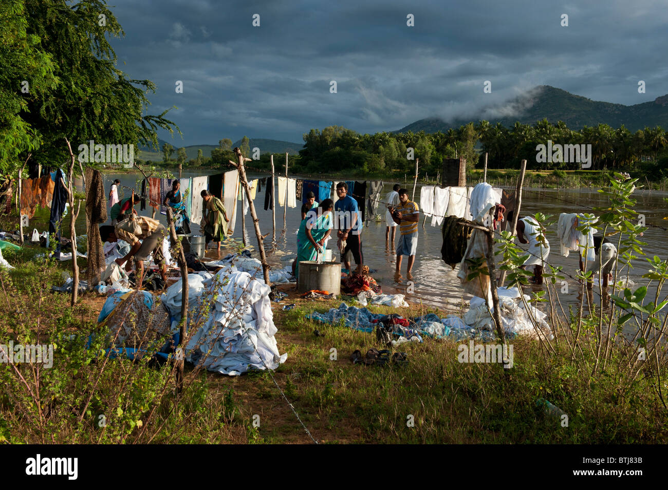 Indian people washing clothes by a flooded river in the town of Puttaparthi, Andhra Pradesh, India Stock Photo
