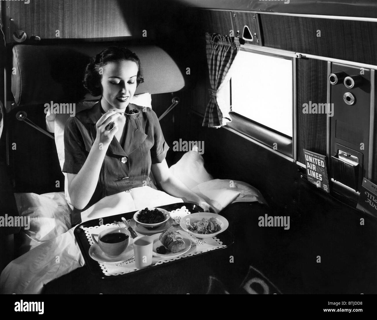 A passenger eats breakfast on United Airline's Douglas Mainliner Sleeper airplane from Chicago to San Francisco, 1937. Courtesy: Stock Photo