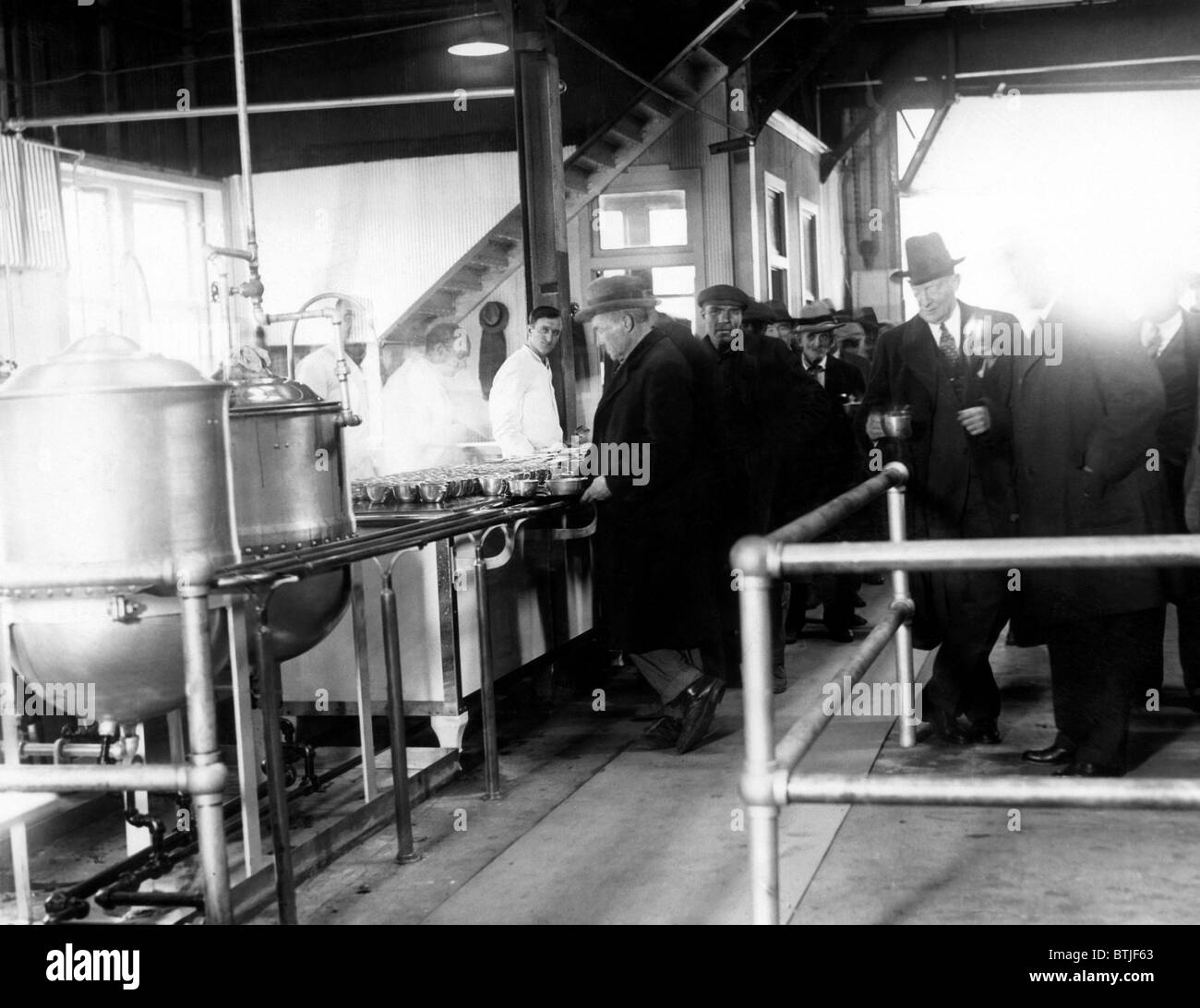 Men wait in line for food at a municipal lodging house. Police Commissioner Edward P. Mulrooney stands with coffee (second from Stock Photo