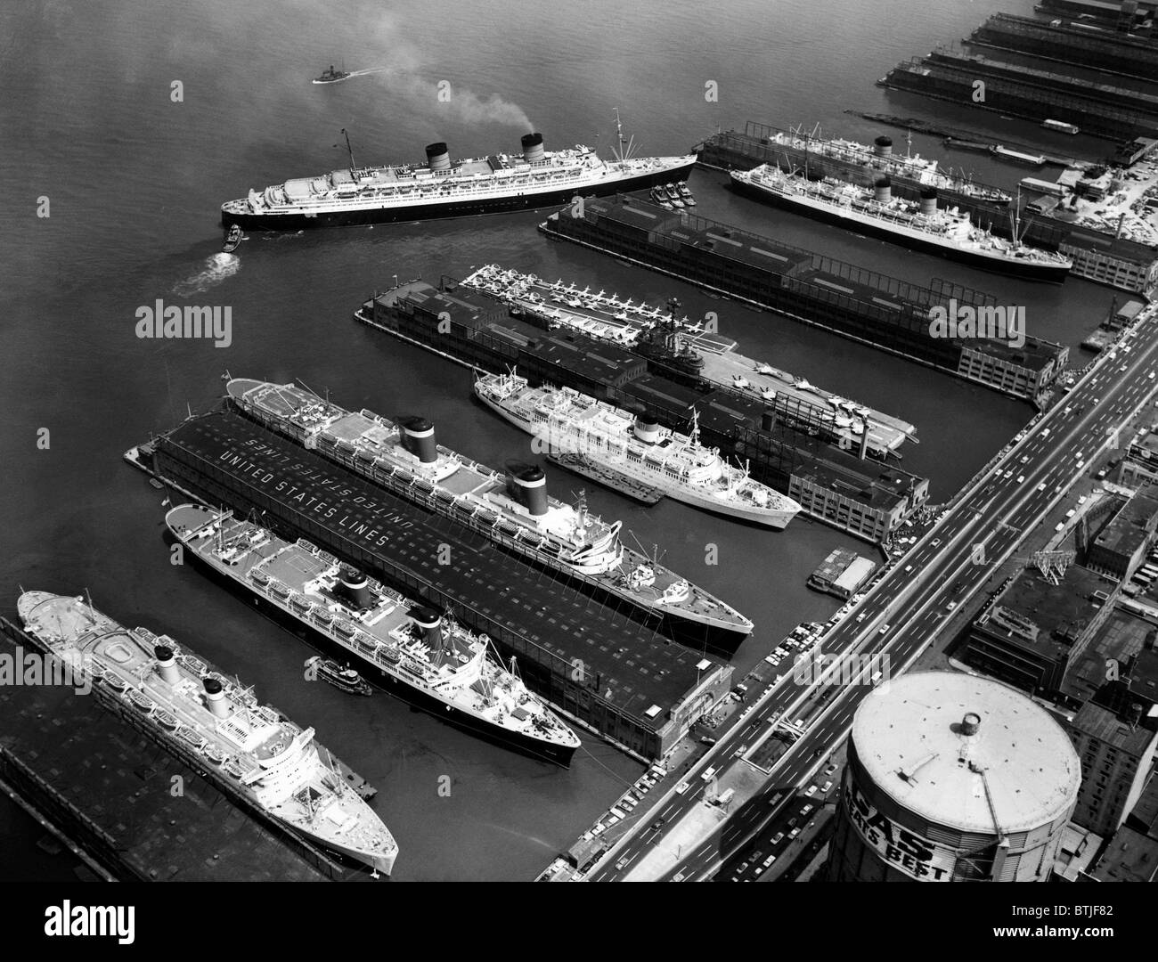 Luxury liners flanking an aircraft carrier at piers along the West Side Highway, from left to right: The Independence, The Ameri Stock Photo