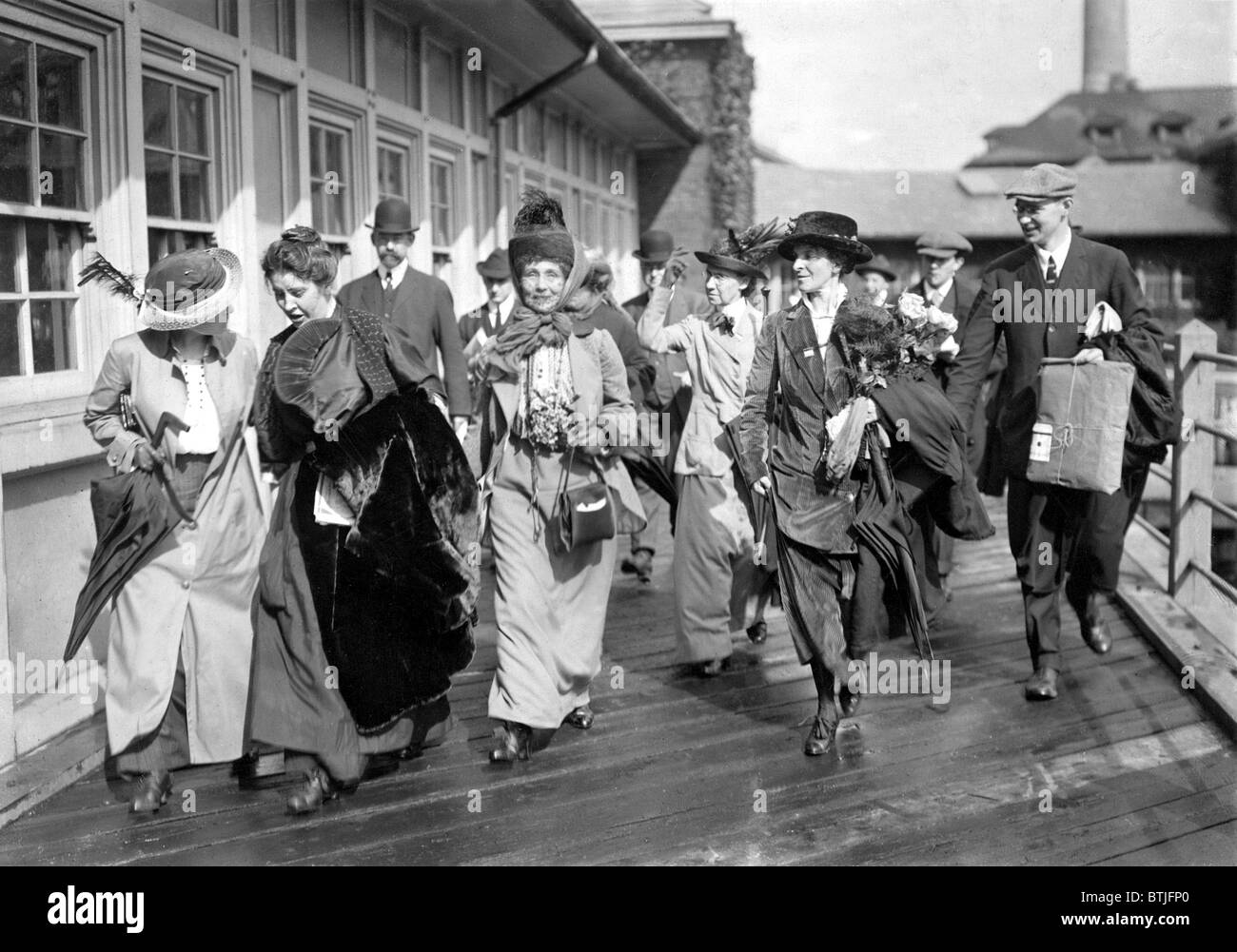 Mrs. Emmeline Pankhurst, the English militant leader (center), is shown leaving Ellis Island today with party of suffragists aft Stock Photo