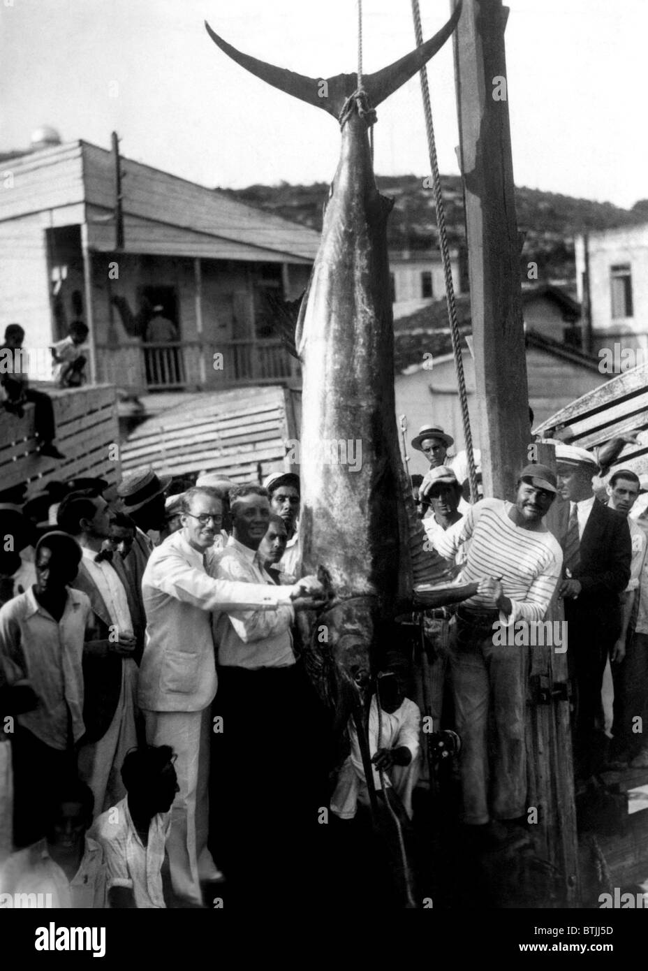 Ernest Hemingway (right) with a record breaking black-marlin caught on a recent fishing trip off the Cuban coast ca. 1935. Court Stock Photo