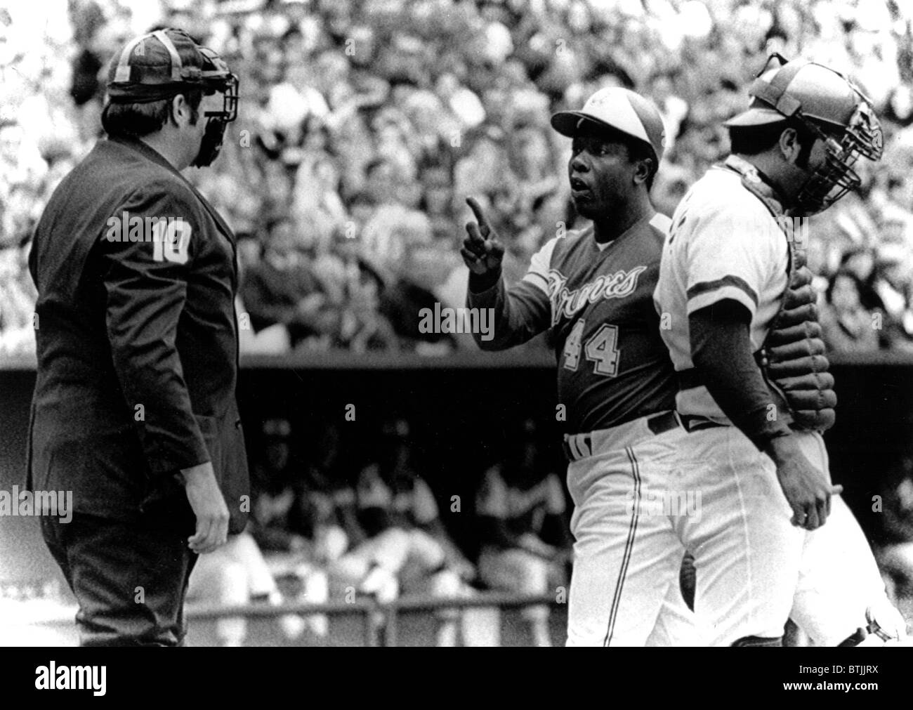 Umpire John McSherry listens to Hank Aaron argue a called third strike as catcher Johnny Bench looks down, 1974 Stock Photo