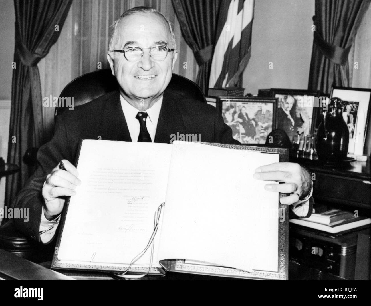 PRESIDENT HARRY TRUMAN holds up the Japanese peace treaty he signed into ratification, 4/15/52. Stock Photo