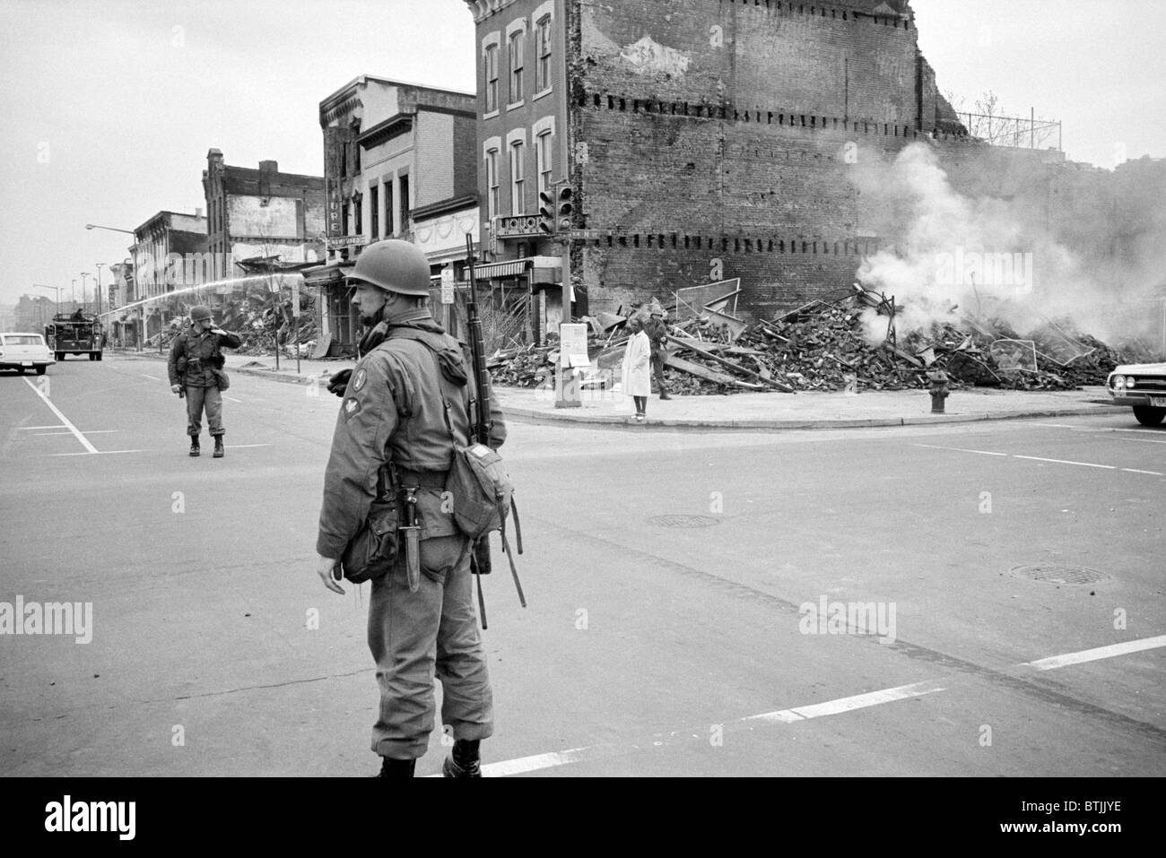 D.C. Riot, April '68. aftermath, soldier standing guard in a Washington D.C. street with the ruins of buildings that were destroyed during the riots that followed the assassination of Martin Luther King Jr., by Warren K. Leffler, April 8, 1968. Stock Photo