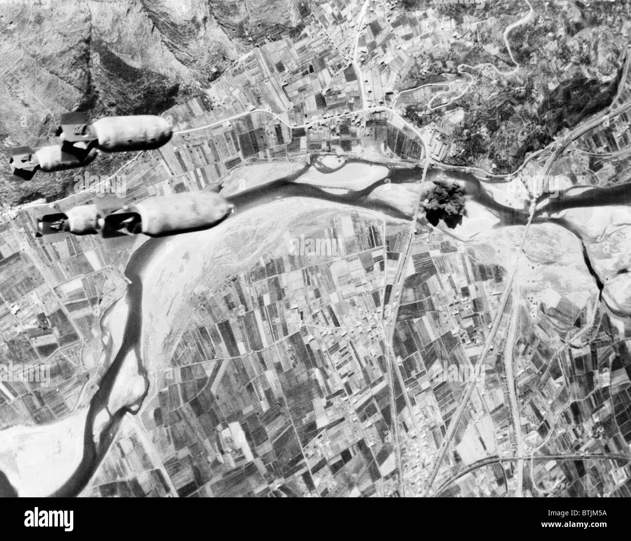 Bombs hurtle toward a Nazi highway bridge. With their rail and shipping facilities almost completely disrupted, the Germans were forced to resort to motor transport. All roads and bridges in central Italy became targets for Allied aerial assaults, ca. 1942-1945 Stock Photo