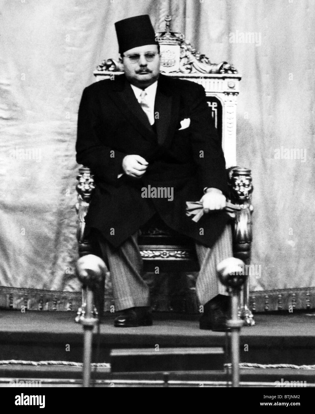 King Farouk of Egypt (1920-1965), listens from his throne as the newly appointed Prime Minister, Mustafa Nahas Pasha delivers a Stock Photo