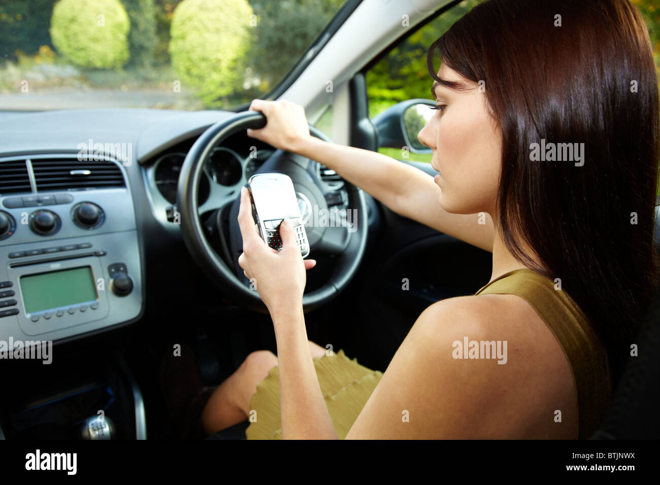 Woman driving and using mobile phone Stock Photo