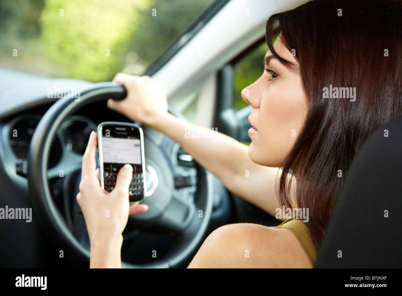 Woman driving and using mobile phone Stock Photo
