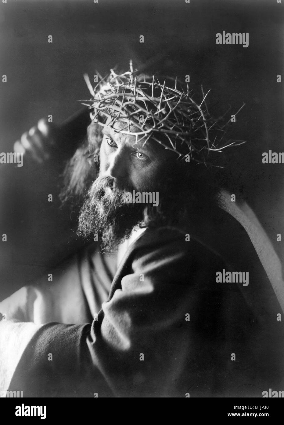 Jesus Christ, man personifying Jesus Christ, wearing crown of thorns and carrying cross, circa 1910. Stock Photo