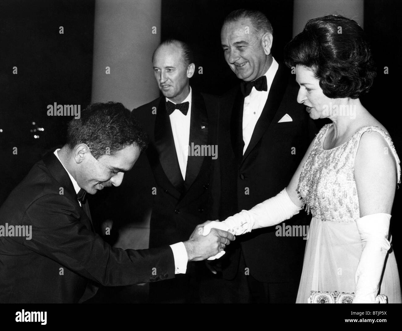 King Hussein of Jordan bows as he is greeted at the White House by Augier Biddle Duke, President Lyndon B.Johnson, and his wife Stock Photo