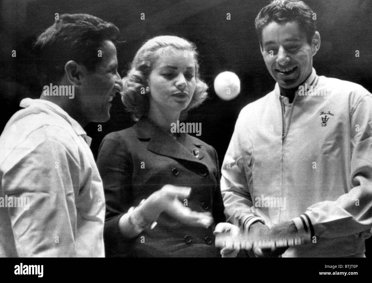 Actress Lauren Bacall serves up ball to pro tennis king Pancho Gonzales as pro ace Pancho Segura (left) looks on. February 13, 1 Stock Photo