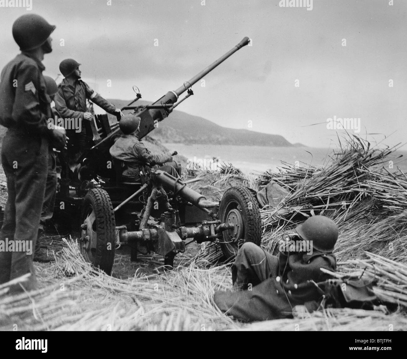 World War II, original caption: 'Anti-aircraft bofors gun in at position on a mound overlooking the beach in Algeria with a United States anti-aircraft artillery crew in position', circa 1943. Stock Photo