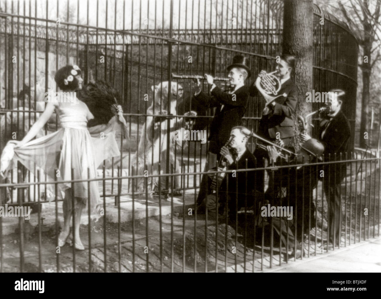 Jazz for the bears, five men playing musical instruments and a woman dancing in front of bears in cage at the National Zoo, Washington D.C, May, 1920-1932. Stock Photo