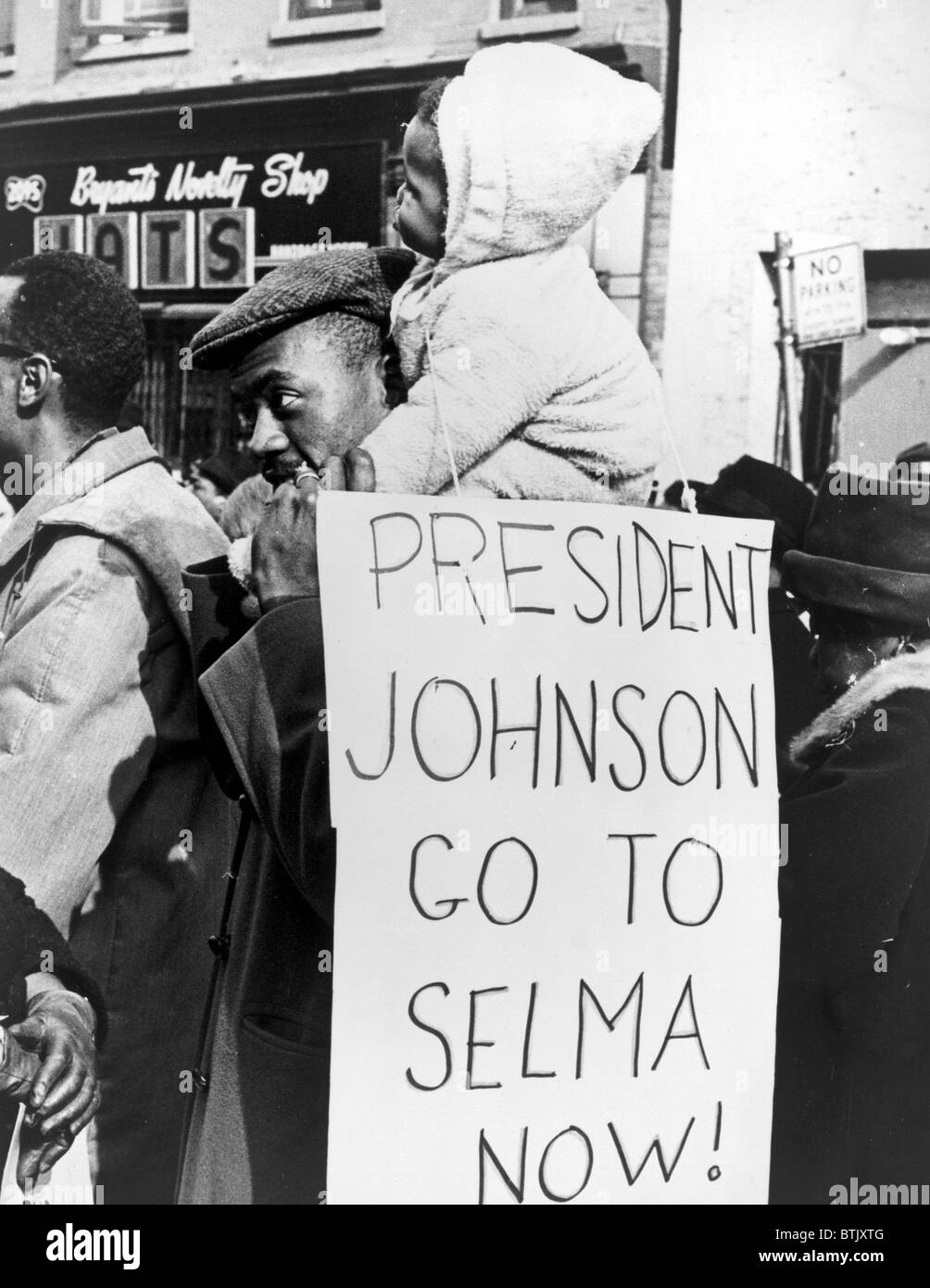 Civil Rights, 'President Johnson go to Selma now!'. African American man carrying a child on his shoulders with a placard telling President Johnson to go to Selma, Alabama. Photo by Stanley Wolfson, 1965 Stock Photo