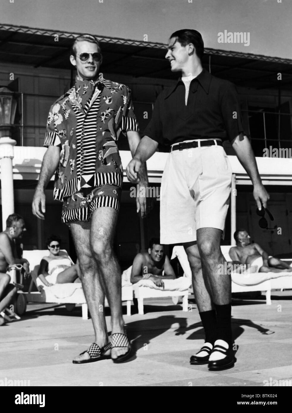 Men wearing the latest beach fashions. On the left, a colorful Mexican design; on the right, longer shorts and an open collar sh Stock Photo