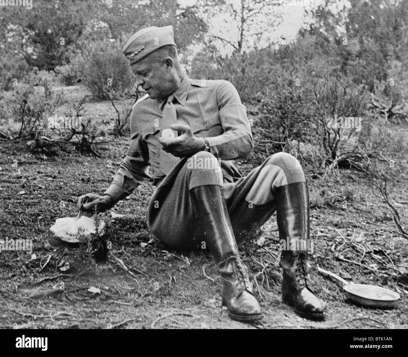 World War II, Future President General Dwight D. Eisenhower (1890-1969), stopping for noon mess by the roadside during an inspection tour in Tunisia. The menu is a C ration, and hot. It was kept warm by being packed next to the manifold of the General's car enroute, photograph, 1943. Stock Photo