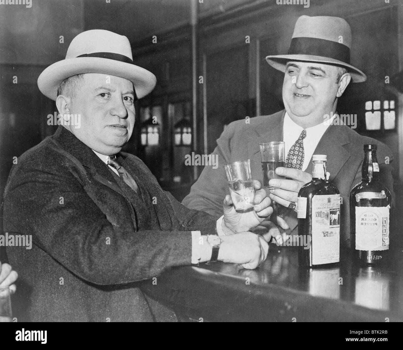 Izzy Einstein (left) sharing a toast with his partner, Moe Smith in a New York bar in 1935. In the 1920's, Izzy and Moe were the most effective team of prohibition agents, using disguises to arrest bootleggers, close speakeasies, and confiscate liquor. Stock Photo