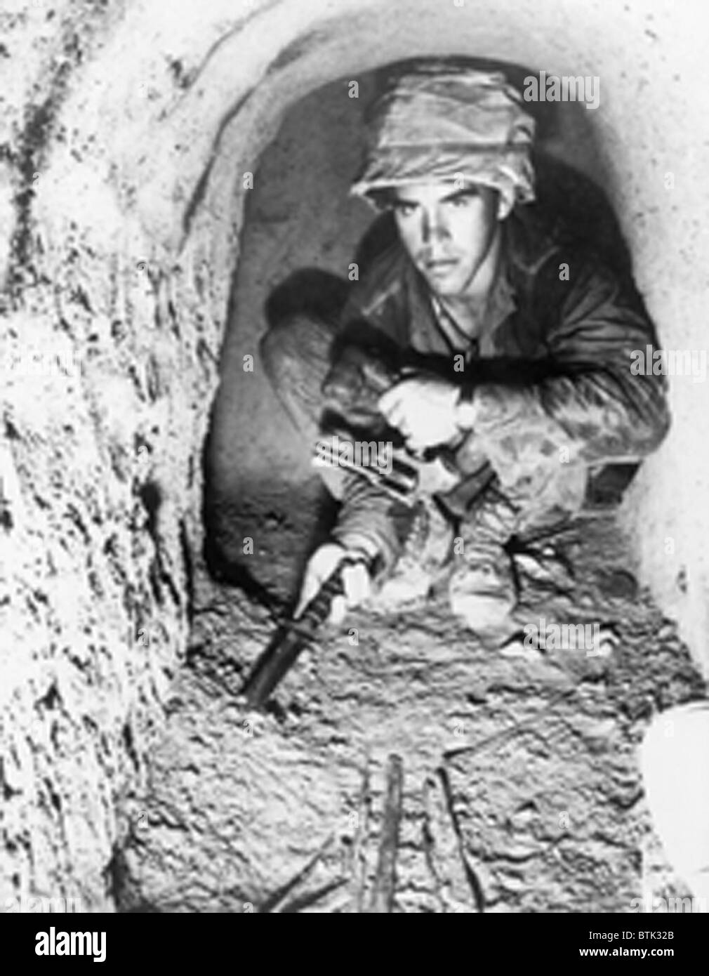 American soldier using a knife to probe the floor of a Viet Cong tunnel in the Iron Triangle north of Saigon, South Vietnam. Jan. 1967. Stock Photo