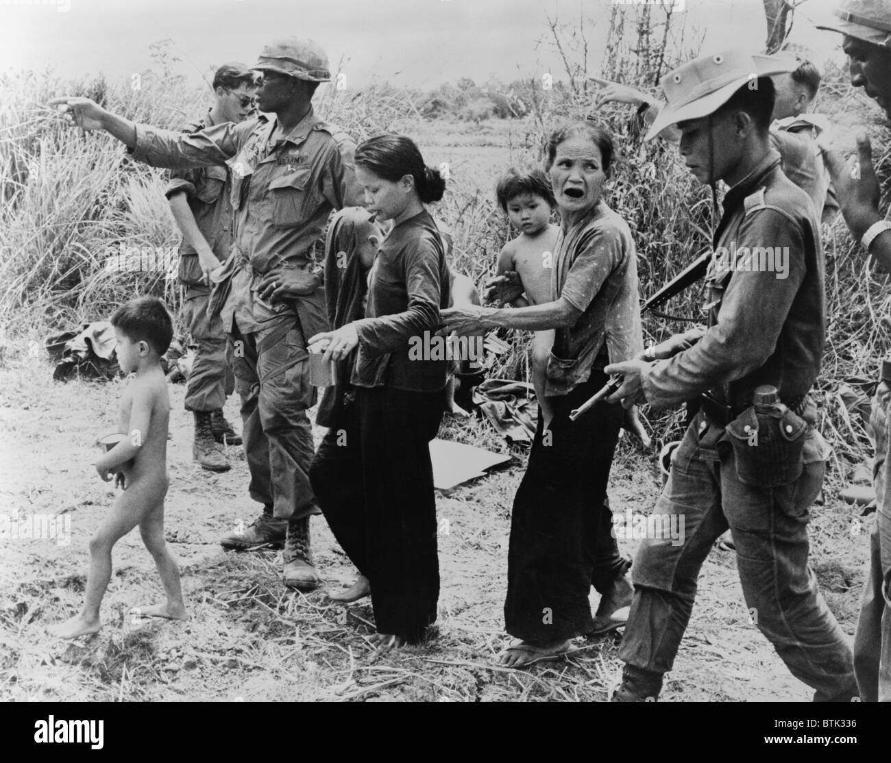 Civilians suffered greatly during the Vietnamese war. In a war zone, American and Vietnamese soldiers direct women and children to 'central collection point for civilians' near the Cambodian border. Stock Photo