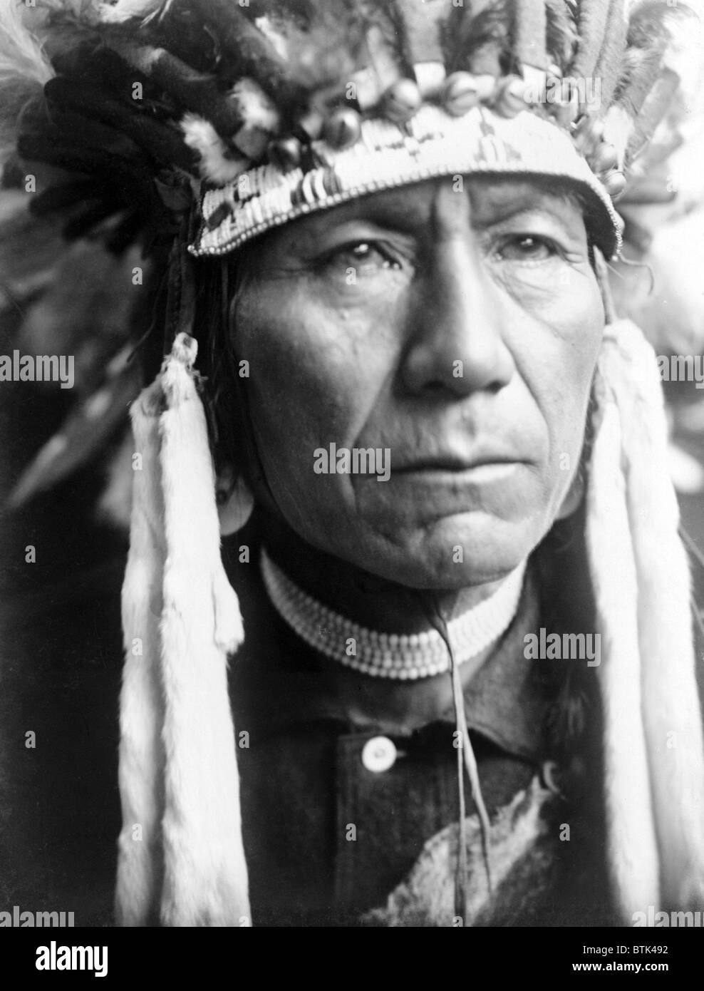 Head-and-shoulders portrait of Nez Percé man in full feather headdress. Edward S. Curtis photo, ca. 1910 Stock Photo